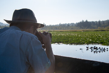 望遠レンズ付けた一眼レフカメラで野鳥撮影をするサングラスをかけたアジア人男性　　バンクーバー　ブリティッシュコロンビア　カナダ
