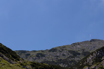 Fototapeta na wymiar View of mountain top in European alps with small man walking on mountain ridge. 