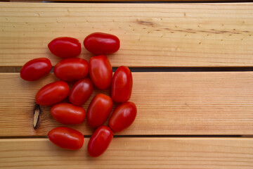 Fresh plum tomatoes on wood rustic background with natural shadow. Top view