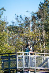 展望台から望遠レンズ付けた一眼レフカメラで写真撮影をするサングラスをかけたアジア人男性　　バンクーバー　ブリティッシュコロンビア　カナダ
