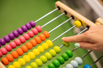 Closeup female hand calculating with balls on wooden rainbow abacus for number calculation. The...