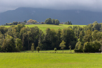 Summer landscape in the mountains. Beautiful lawn and house in mountains. Countryside landscape. Sunny field and mountains in clouds. Pasture and the village. Scenery valley. Farm in the hills.