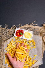 fries-fried potatoes with sauce. vertical photo. a man's hands eat food. flat lay
