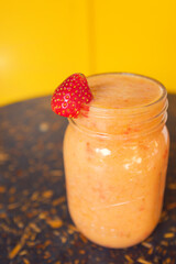 Colorful smoothie with fruit decoration on wooden table with yellow background. Healthy drink concept. Healthy smoothie