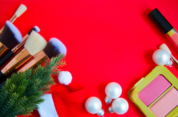 creative Christmas cosmetics flat lay - premium makeup brushes, blush palette, Christmas balls, Christmas tree and Santa hat on a colored red background
