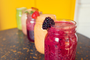 Colorful smoothies with fruit decoration on wooden table with yellow background. Healthy drinks concept. Healthy smoothies.