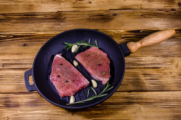 Raw steaks with garlic, rosemary and spices in a cast iron grill pan