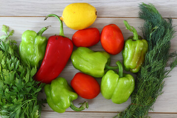 Red pepper, green pepper, tomato, parsley, dill, lemon on a brown wooden background top view, fresh vegetables,