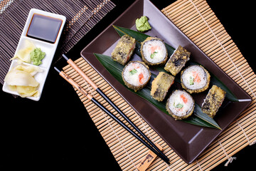 Set hot rolls with avacado, salmon, cream cheese, seaweed, soy sauce, ginger on a dark table. Sushi