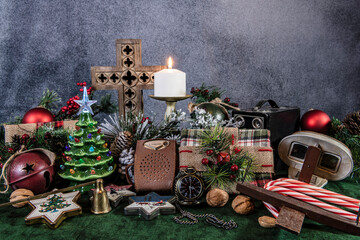 still life vintage Christmas presents and decorations on green with burning candle and cross