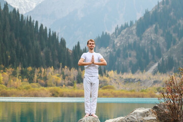 Young zen man in meditation. Outdoor yoga in mountain lake