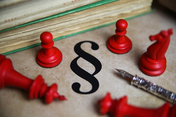 Closeup of isolated paragraph symbol on old yellow vintage paper with books, ink pen and red chess...