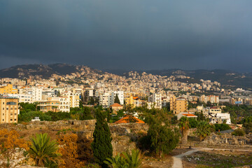 Obraz premium Excavations and modern part of the city of Byblos, Lebanon. Panoramic views of the city and mountains in a dramatic sky. Beautiful landscape at sunset