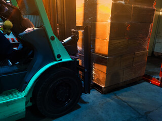 Worker driving forklift loading and unloading shipment carton boxes and goods on wooden pallet from...
