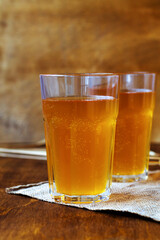 Homemade bread kvass on brown background. Summer soft drink. Glass of beer with sackcloth on a wooden table. vertical