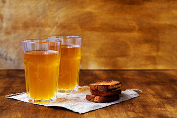 Summer soft drink. Two glass of homemade bread kvass with copy space. Beer with sackcloth on a wooden table with black rye bread hard chucks.