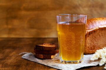 Glass of homemade bread kvass with black rye bread on a wooden table. Beer with sackcloth. copy space. summer soft drink.