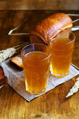 Summer soft drink. Two glass of homemade bread kvass. Beer with sackcloth on a wooden table. Black Overseas Rye Bread - Ingredients for a Drink. vertical