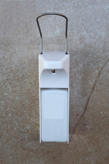 White dispenser of anesthetic solution on a marble wall. Prevention of the coronavirus pandemic.