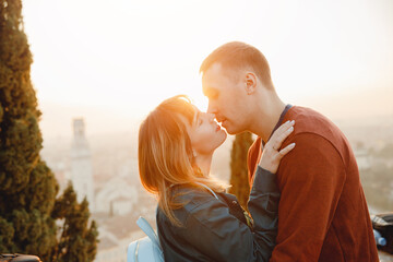 Romantic couple man and girl hug and kiss on sunset background of city Verona Italy. Travel concept