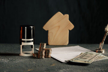 Miniature house with money and tax papers.