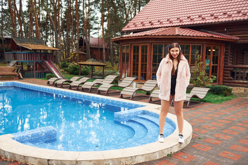 Woman posing outdoors near pool against building exterior