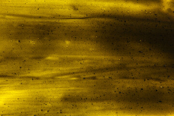 Black smears charcoal toothpaste over yellow board, abstract background