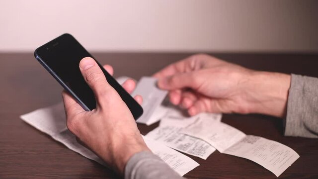 Online payment. Man's hands holding smartphone and using three different credit cards for online shopping, then checking the invoice
