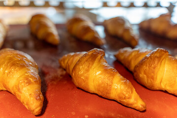 Fresh golden croissants lie on a red tray