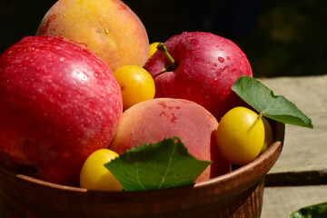 There is a plate of peaches and apples on a table built from old planks.