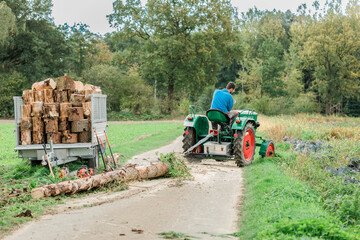 Man pulling tree trunk with tractor