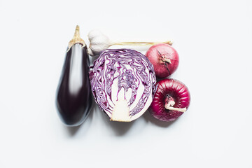 top view of red onion, red cabbage, eggplant and garlic on white background