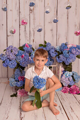 Happy baby boy in the studio on a white background with pink and blue hydrangea flowers