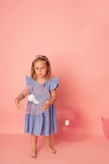Happy baby girl on a pink background with balloons. Celebration. Birthday