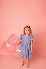 Happy baby girl on a pink background with balloons. Celebration. Birthday