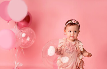 Obraz na płótnie Canvas Happy baby girl on a pink background with balloons. Celebration. Birthday