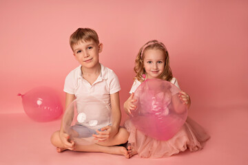 Happy child girl and boy on a pink background with balloons. Celebration. birthday