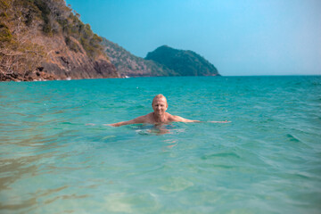 adult man swims in the sea against the background of mountains, summer sea holidays, travel and tourism.Vacation in Asia