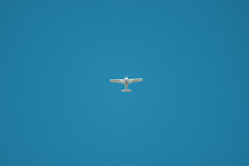 in the blue cloudless sky one  small white propeller plane flies