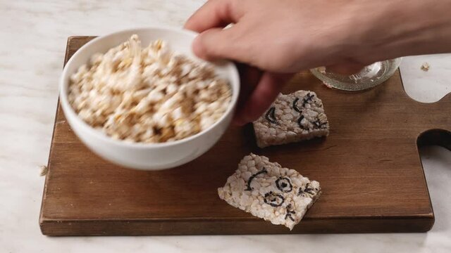 Man pouring crispy sweet rice from jar into bowl on table
