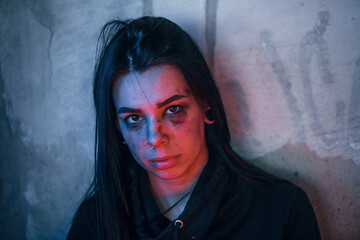 Portrait of beaten young woman with bruise under eye indoors in abandoned building