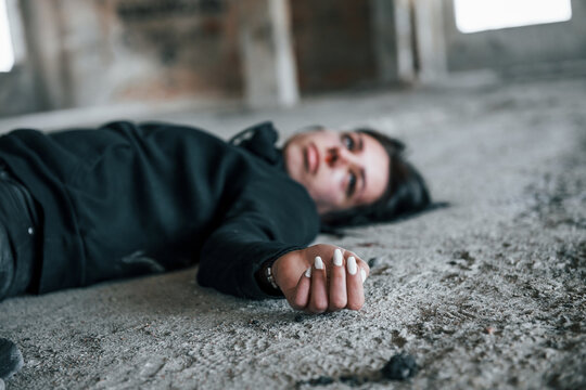 Corpse of female victim of crime lying down on the ground of abandoned building