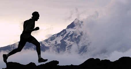 Running man athlete trail running in mountain summit background. Male runner on run training outdoors living active fit lifestyle. Silhouette at sunset. © Maridav