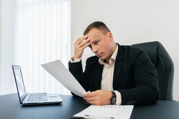 The thoughtful man at work reads from a piece of paper.