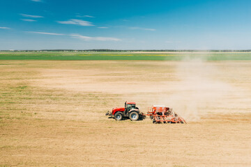Obraz premium Aerial View. Tractor With Seed Drill Machine Sowing The Seeds For Crops In Spring Season. Beginning Of Agricultural Spring Season. Countryside Rural Field Landscape