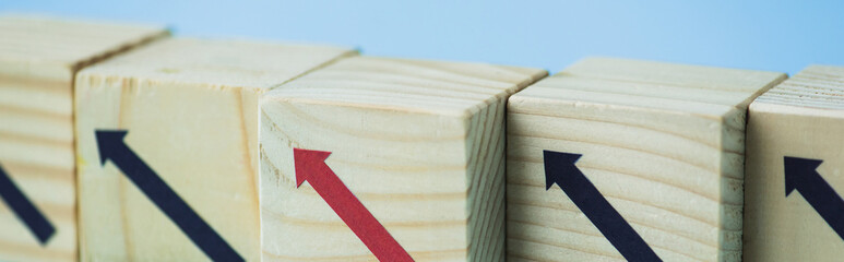 close up view of wooden blocks with black and red arrows on blue background, leadership concept, panoramic shot