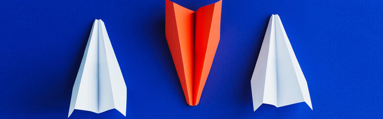 flat lay with white and red paper planes on blue background, leadership concept, panoramic shot