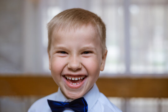 Portrait of a boy in white shirt and black bow tie, smiling cheerful schoolboy