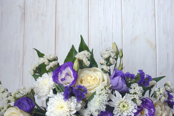 Beautiful bouquet of white and purple flowers on a white wooden background. Flower arrangement for...