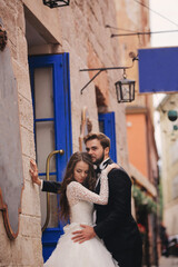 Wedding couple hugging in the old city. Blue vintage doors and cafe in ancient town on background....